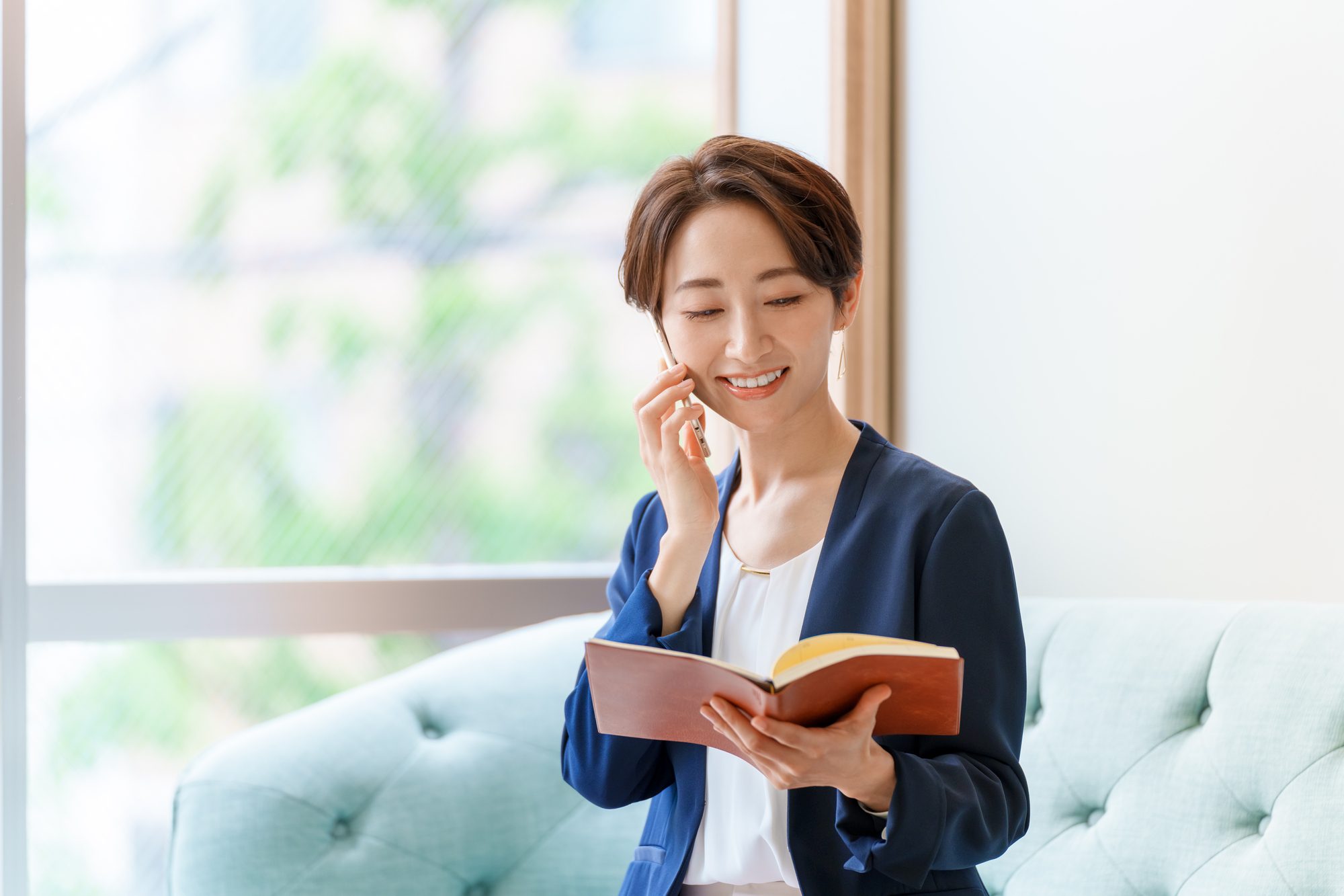 スケジュール帳を見ながら電話するビジネスパーソン