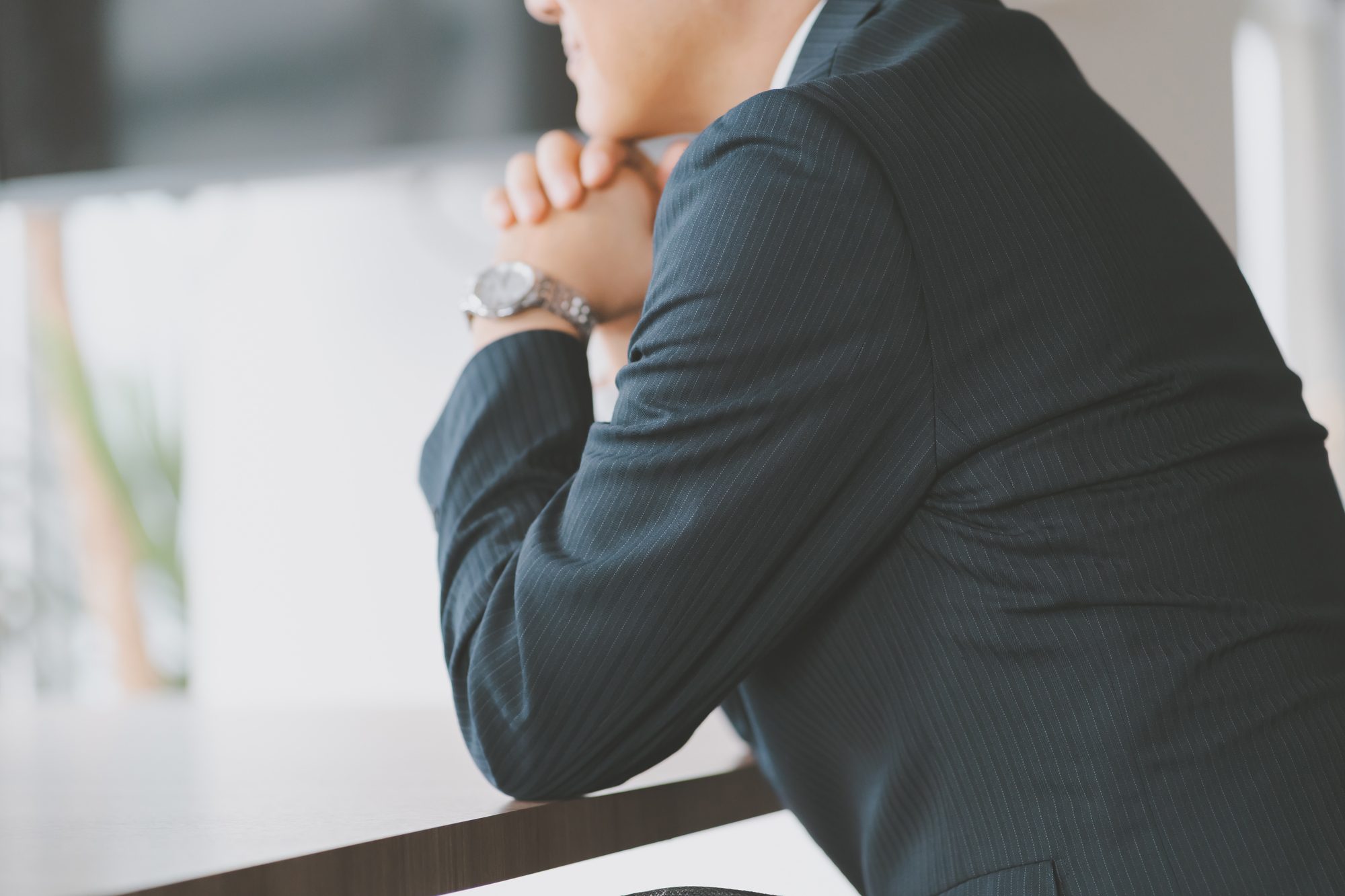机に肘をつき施行するビジネスパーソン