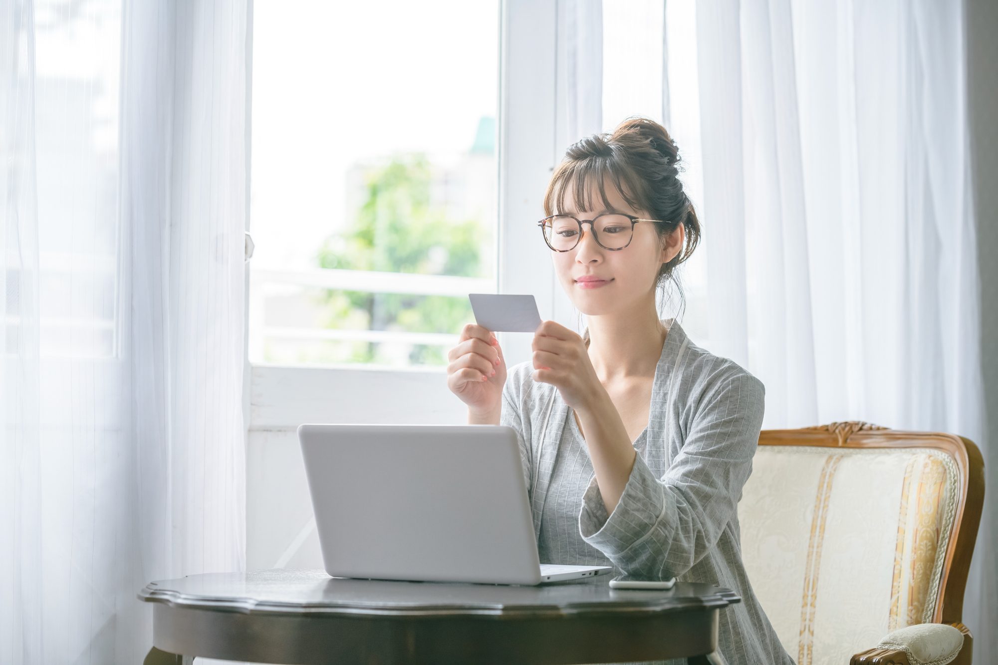 パソコンを前にキャッシュカードを手にしている人物