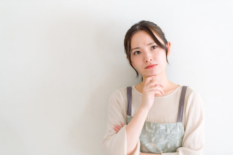 考え事をするエプロンをつけた人物