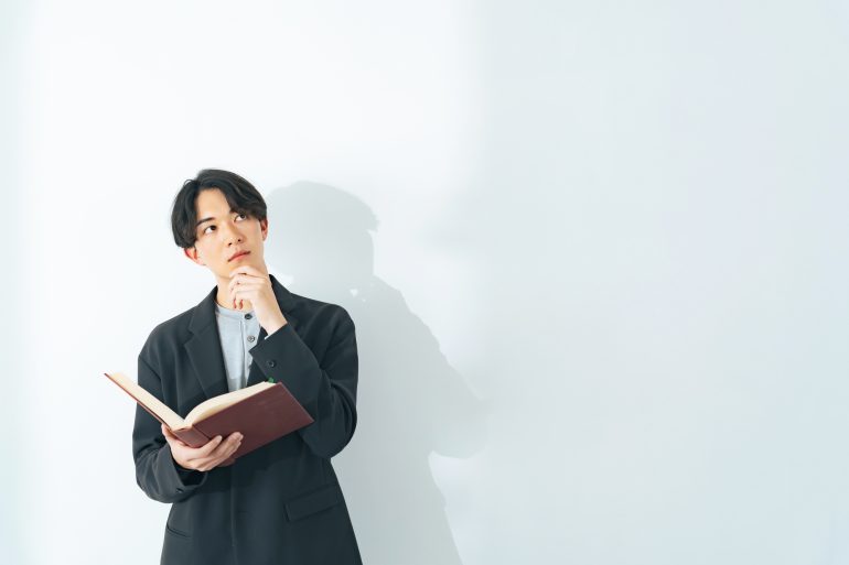 本を手に考え事をする人物