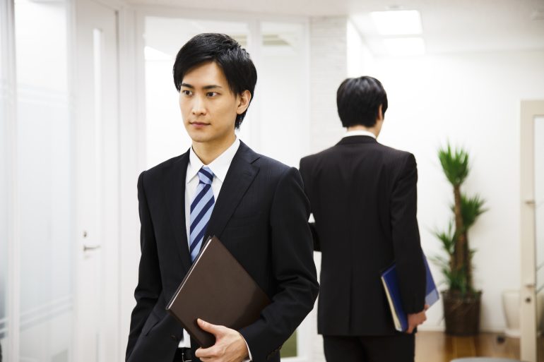 廊下ですれ違うビジネスパーソン