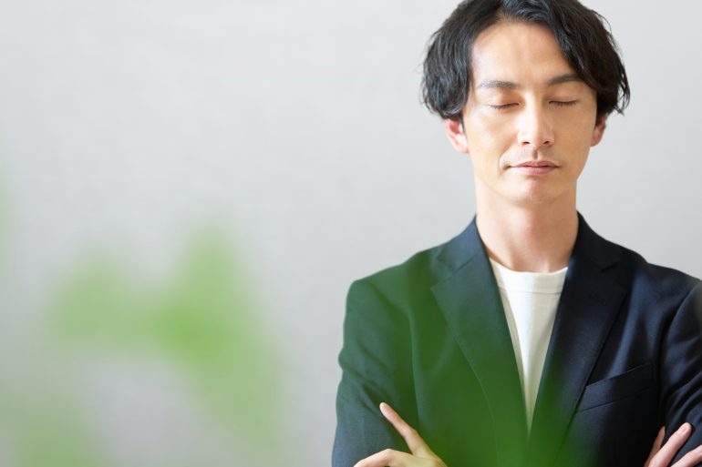 目を閉じるビジネスパーソン