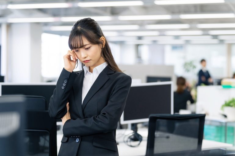 暗い顔で電話をかけるビジネスパーソン