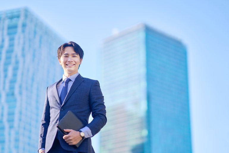 ビルを背景に建っているビジネスパーソン