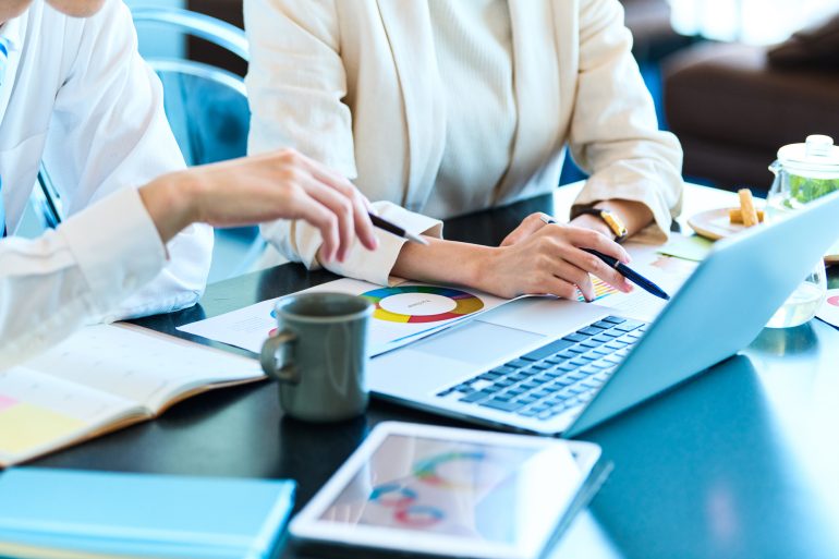 パソコンを見ながら打ち合わせをする