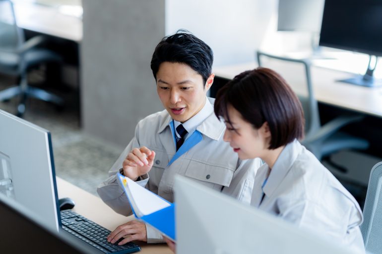 書面を見ながら話す二人のビジネスパーソン